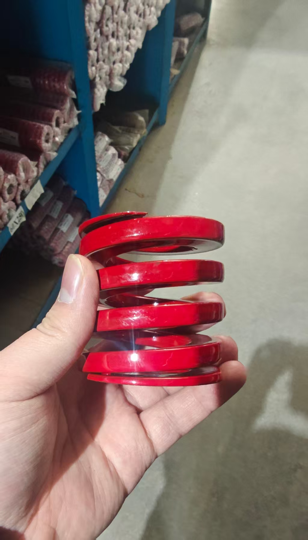 手持红色矩形线压缩弹簧展示端部和圈间间隙